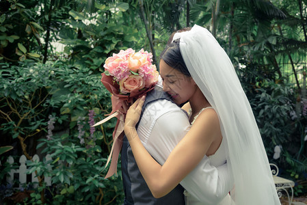 结婚夫妇新郎和娘美丽的女人和男拥抱彼此着花束爱情和人观念外部调订婚图片