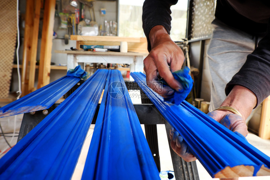 在车间工作的越南男子手在木棍上涂着蓝色漆彩料人们自己在越南达拉特做家用具店铺亚洲人在职的图片