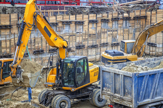 土方重的桶挖掘机正在卡车上装载挖掘作业建筑工地的重型设备在施工中进行作图片