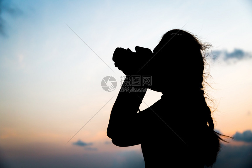 橙水以日落背景拍摄照片的Silhouette摄影师相机图片