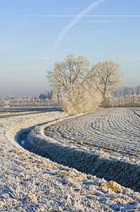 圩田一条弯曲的沟渠环绕着一片冰冻的田地在明晴冬天粉彩交通图片