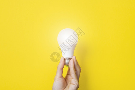 技术解决方案效率手拿着亮黄色背景的LED灯泡使用经济环保的灯泡概念理女手中的节能灯带有复制空间的横幅手拿着亮黄色背景的理念带复制图片