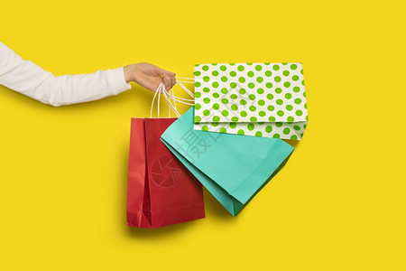 购物或销售概念女手拿着黄色背景上隔离的购物纸袋横幅女手拿着黄色背景上隔离的购物纸袋包店铺时尚图片