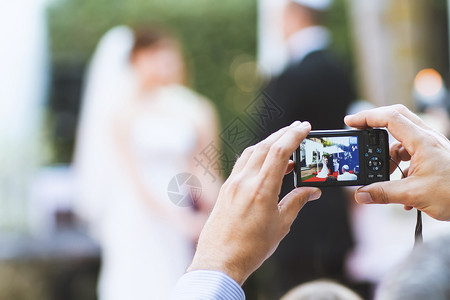 快照一种袖珍的客人用照相机手拍新娘和郎的照片在婚礼仪式上照相图片