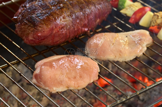 正面两片猪肉和牛和蔬菜饼叉在选择焦点下烧烤与发光木炭重点放在第一块猪肉切片的前面牛扒文化图片