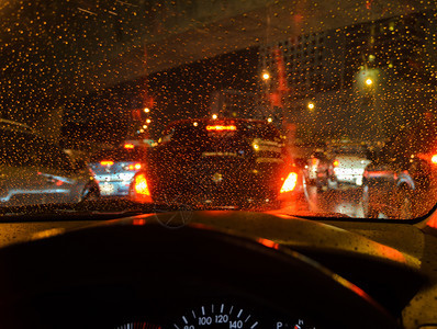 街道夜间下雨时在湿风屏上看到蓝色驾驶车散景交通图片