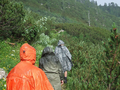 男人女孩一群穿着雨衣的游客在山上徒步旅行游概念人们穿越森林和山脉一群穿着雨衣的游客在山上徒步旅行游概念徒步行者图片