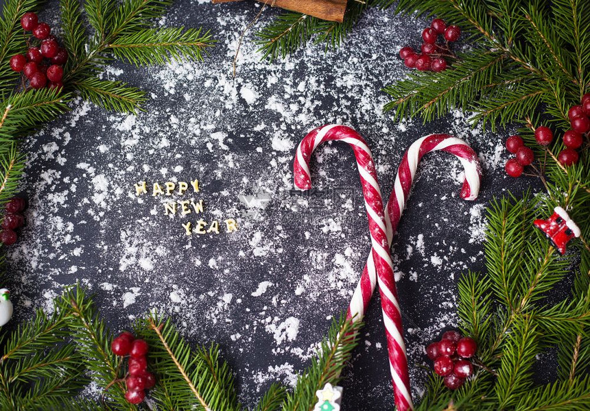 季节卡片圣诞或新年装饰背景为树枝黑色背景上的糖果圣诞节或新年装饰背景为树枝黑色背景上的糖果白色图片