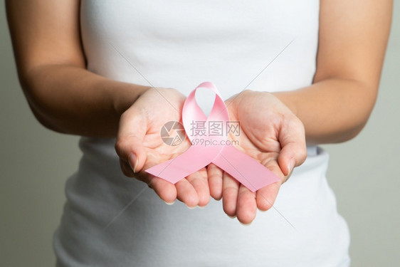 手拿粉色丝带的女性预防癌症概念图片
