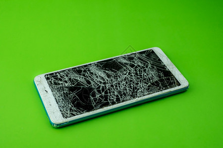 裂缝聪明的智能手机屏幕在绿色背景下破解劈开图片