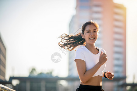 早晨马拉松亚洲青年健身运动女在城市公路上奔跑和微笑人背景