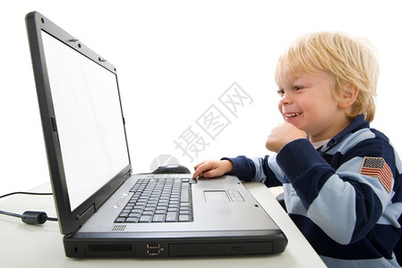 在室内工作里面一个小男孩用笔记本电脑坐在档案中他笑着从腰部向上可看见望着镜头远一点在横向拍摄的屏幕上图片