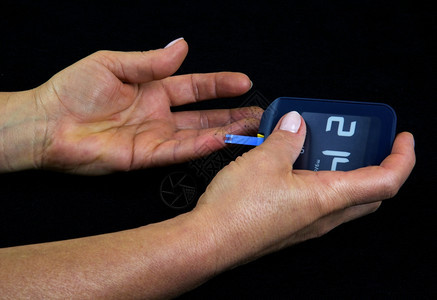 白种人先进的样本一位使用葡萄测量仪血糖水平的尿病高位妇女明显可见在条状测量时间上有一滴血手指上有黑点色水平视图中隔开的长打指结柱图片