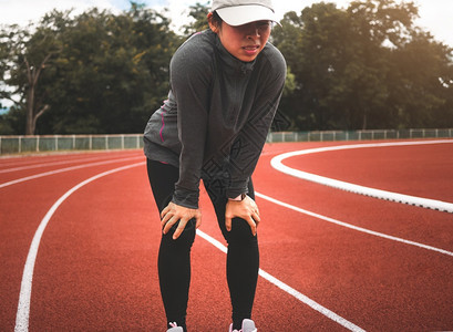 运动服疲倦的女跑者在体育场田径追逐运动赛跑后休息健康生活方式概念马拉松户外图片