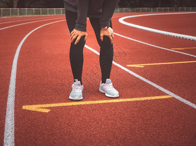 竞赛红色的活动疲倦女跑者在体育场田径追逐运动赛跑后休息健康生活方式概念图片