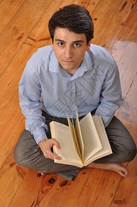 男木制的在家坐地板上看商业书的有吸引力年轻男青在阅读商业书籍现代的图片