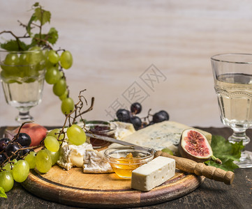小吃木头羊乳干酪卡门塞特多蓝高贡佐拉蜂蜜葡萄和酒放在木制生锈背景最接近的顶端视野上图片