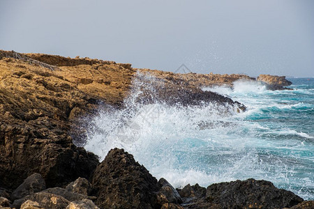 碰撞海浪击塞浦路斯岛卡帕阿波托洛安德列亚海滩的岩石黑色水图片