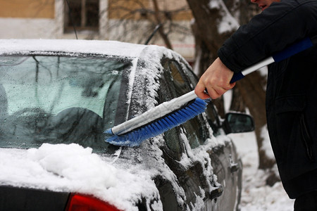 活动冬天雪车季问题男人在特殊的刷子帮助下从雪中清理汽车工作街道图片