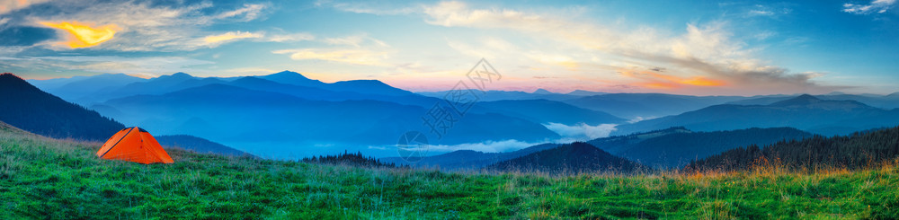 天空绿草风景山平原上的全景橙色帐篷图片