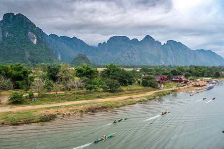 河边皮艇万老挝VangVieng的南宋江旅游船和山背景象图片