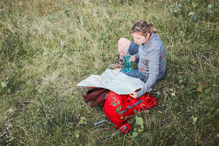 户外漫游者在山上旅行时背包有间休息的妇女在暑假日看着坐草地上的图远足图片