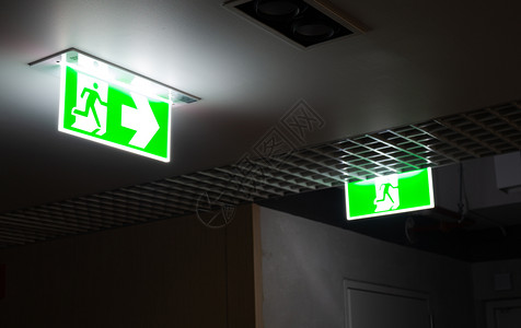 建造晚上在办公室的天花板上挂着绿色防火逃生标志警告墙图片