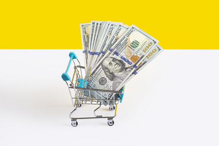玩具超市手推车或购物满是在黄色和白背景上隔离的钱货币贷款或销售概念横幅与复制空间买金融消费者图片