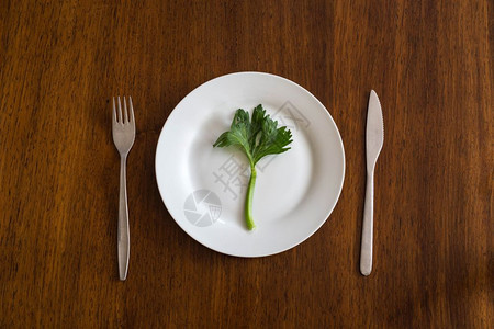 桌子空白板上的绿蔬菜在木板上煮吃健康最高视力食物的概念在空白板上吃绿色蔬菜在木板上用女手切菜身体健康白色的餐具图片
