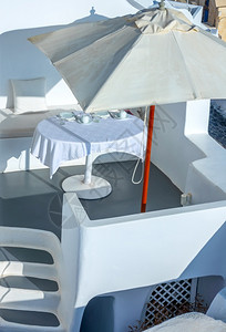 晴天圣托里尼岛卡路德拉的希腊阳光夏日在户外大太阳伞和服务台下的太雨供餐桌盘子清爽图片