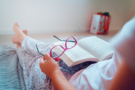 女士白色的紧贴在坐家庭后视的地板上阅读或学习时持有书本和眼镜的女孩或妇中间部者知识图片