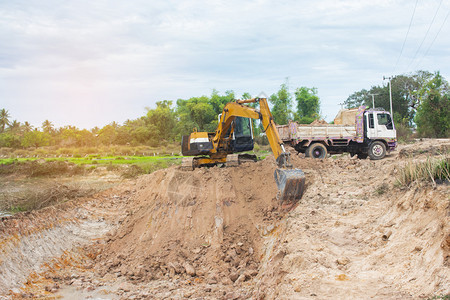 黄色挖掘机将土壤装入建筑工地的倾卸卡车中运输力量地球图片