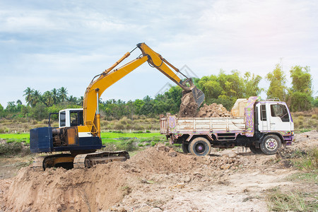 项目自卸车路黄色挖掘机将土壤装入建筑工地的倾卸卡车中图片