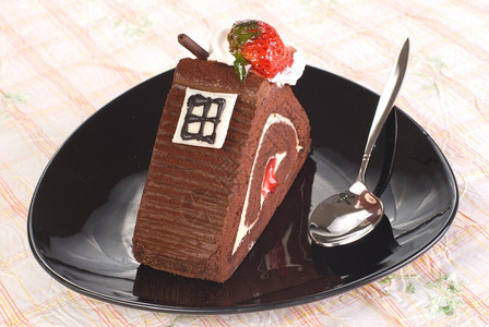 一块巧克力蛋糕餐桌上黑盘里有草莓的巧克力蛋糕水果面包店可口图片