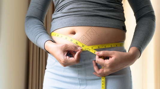超重肥胖妇女手握测量胶带记录她的腹部脂肪妇女饮食生活方式建立肌肉概念健康分数图片
