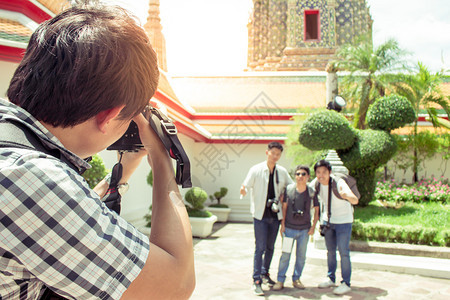 亚洲黑色的涉水男游客在泰国寺庙里拿着相机拍照并朋友片图片