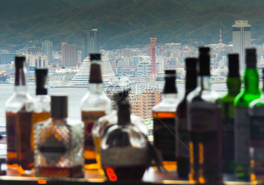 喝娱乐JAPANKOBEAPRAIL1207年神户塔和城市天际线在街对神户市天际线上用模糊的威士忌瓶子与模糊的威士忌瓶子对抗神户图片