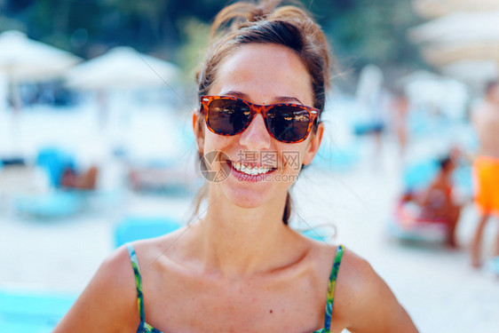 户外愉快年轻美女的肖像站在海滩上阳光明媚的暑夏日戴着墨镜在假期微笑时穿着太阳眼镜支撑图片