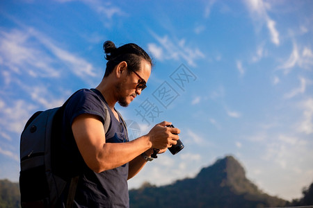 亚洲人男子旅游者正在使用照相机拍摄风景和山地休闲时间的摄影照片以
