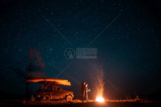 欢乐的情侣女站在星空前燃起的营火中享受着宁静的夜晚图片