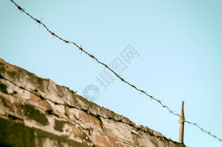 铁墙建筑学砖墙和蓝天空上有铁丝网的围栏砖墙上有铁丝网的围栏安全预防背景