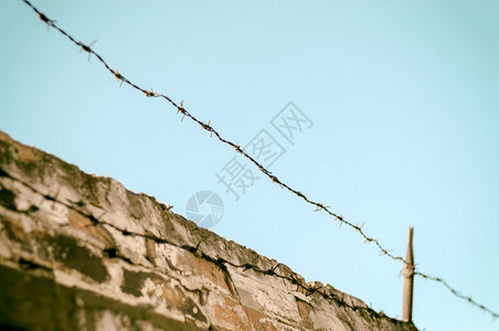 建筑学砖墙和蓝天空上有铁丝网的围栏砖墙上有铁丝网的围栏安全预防图片