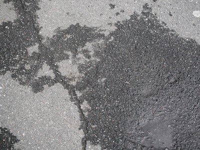 地面黑色的破碎沥青雨后有水坑城市肮脏的高清图片素材