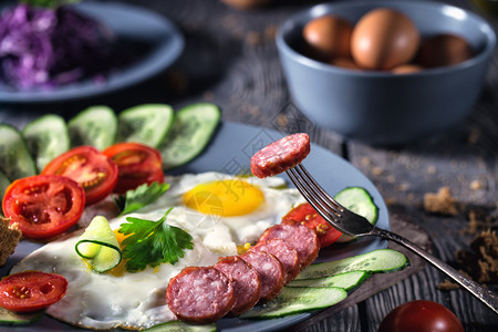 晚餐烧焦节食桌上有蔬菜和香肠的炒鸡蛋健康食品的概念早餐生菜式饭桌上有蔬菜和香肠的炸鸡蛋背景图片