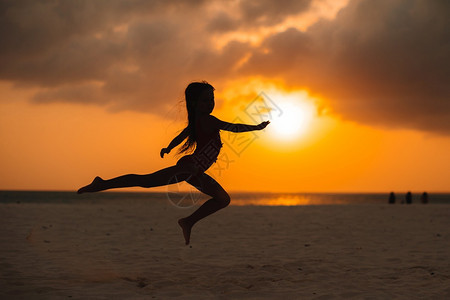 日落时在白沙滩上可爱的快乐小女孩日落时在白沙滩上美丽的快乐小女孩运动海岸晚上图片
