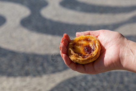 在葡萄牙里斯本的背景点上葡萄牙传统妇女手中的Pasteisdenataspathesnata甜点美食曲奇饼图片