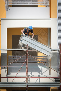 男戴蓝色安全帽的工人在建筑地的脚手架上作一名建筑人在地的脚手架上作为了行业图片