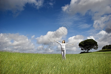 明亮的多云一种女人在美丽的绿草地上放松图片