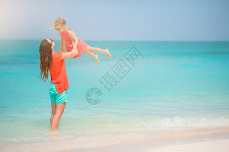 加勒比海年轻美丽的母亲和可爱小女儿在热带沙滩玩得开心享受暑假的美丽母亲和女儿在沙滩上过着愉快的时光海滩活图片
