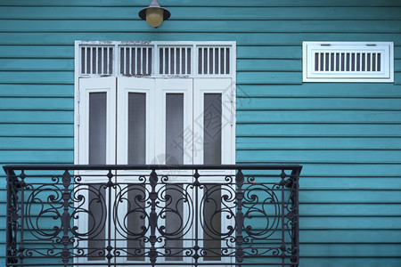 丰富多彩的传统黑色阳台白木制门有通风口和墙灯的白木门蓝色制墙壁上用古老的音调风格建造颜色图片
